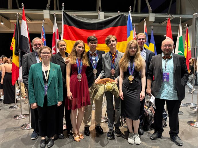 Die deutsche Delegation mit dem Maskottchen der IBO: (v.l.n.r. Burkhard Schroeter, Annabel Maisl, Christiane Mühle, Leonore Fischer, Leon Chen, Elias Fischer mit der Schildkröte Bo, Franziska Maier, Jan Kruse, Jan Krieghoff)