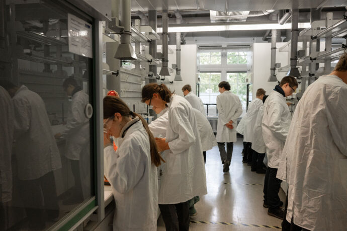SchülerInnen bei der Laborarbeit unter der Aufsicht eines Betreuers 